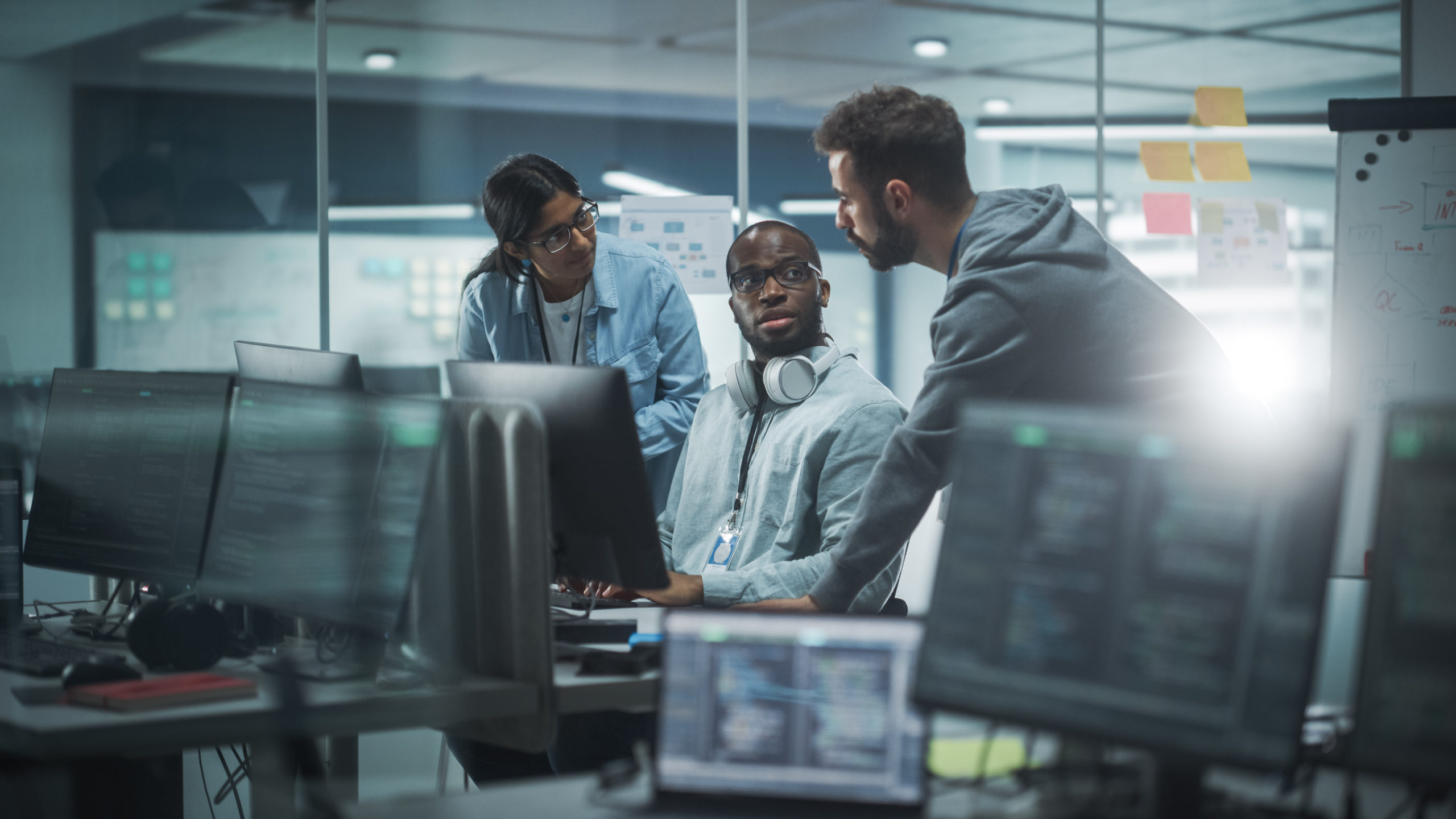 Software developers strategizing around a computer in a modern office